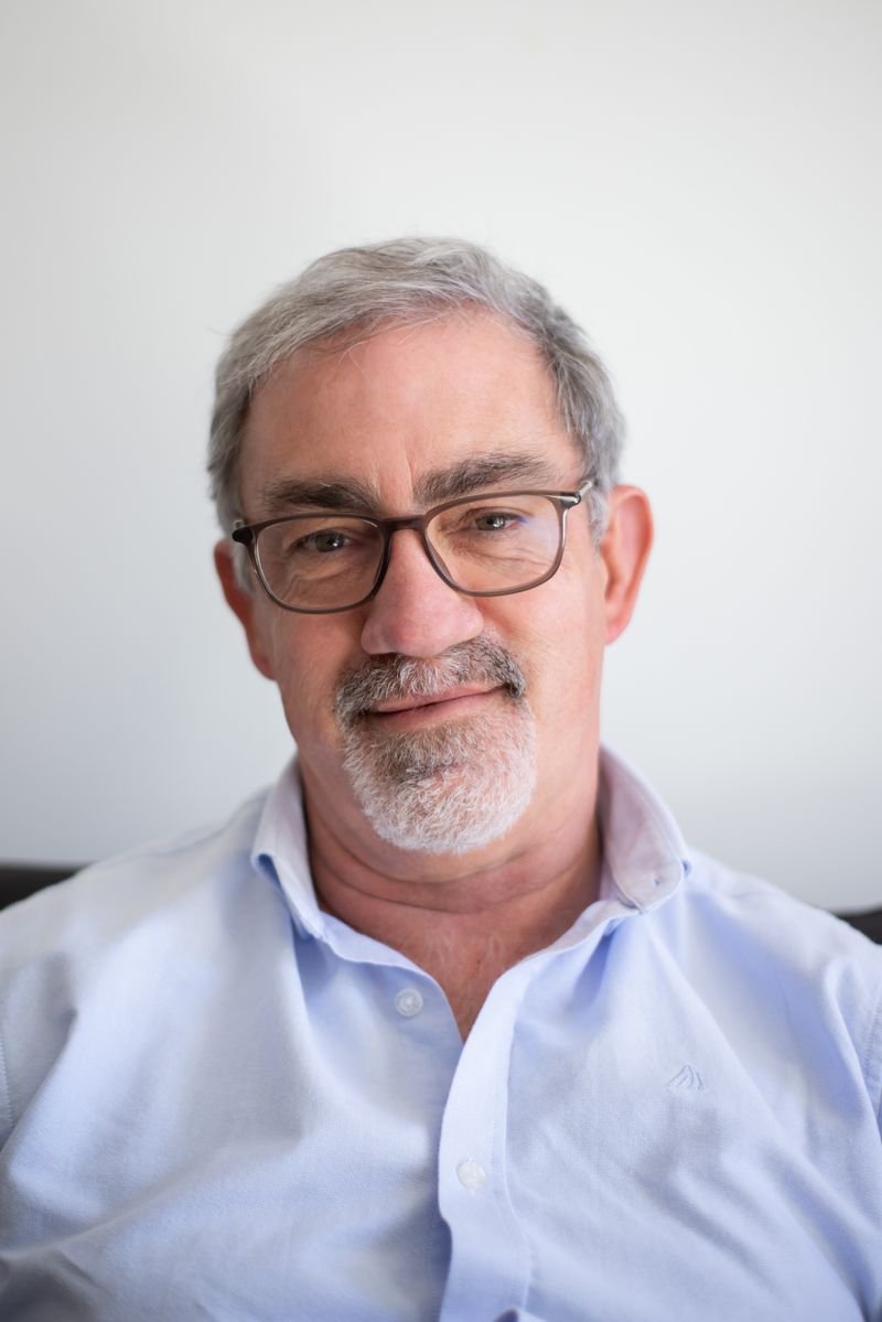 Dr. Otávio Benevides, cardiologista, de óculos e camisa azul-clara, sorrindo