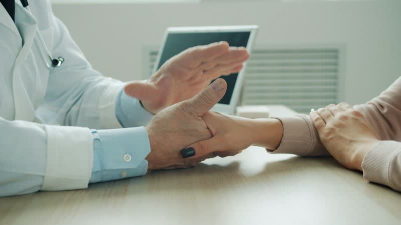 Mãos de médico e paciente sobre a mesa durante uma conversa
