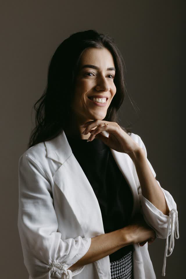 Dra. Lívia Montenaro, fundadora da Corlina, sorrindo com a mão apoiada no queixo
