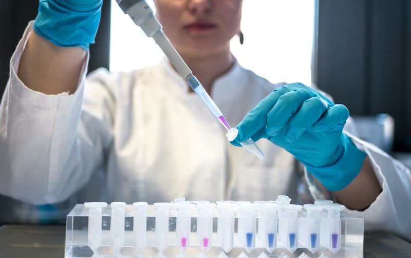 Profissional de laboratório usa uma pipeta sobre tubos de amostra